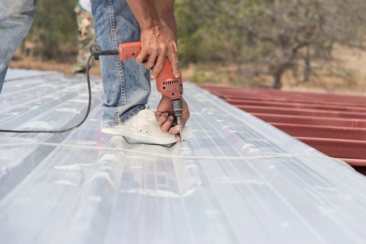 A man is using an electric saw to cut the roof.